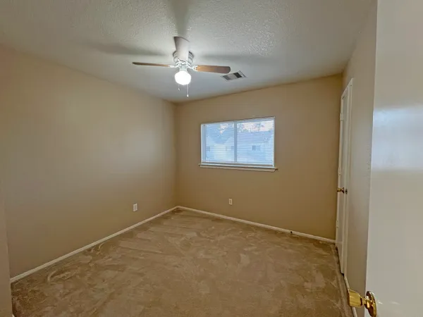 a view of an empty room with a chandelier fan