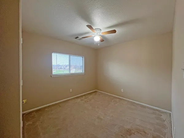 an empty room with a window and a fan