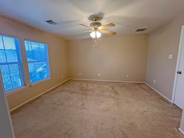 an empty room with windows and fan
