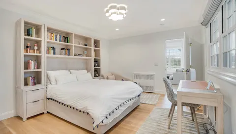 a bedroom with a bed chandelier and a window