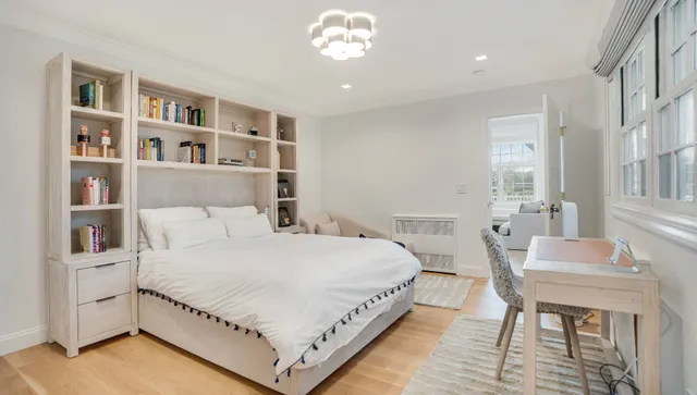 a bedroom with a bed chandelier and a window