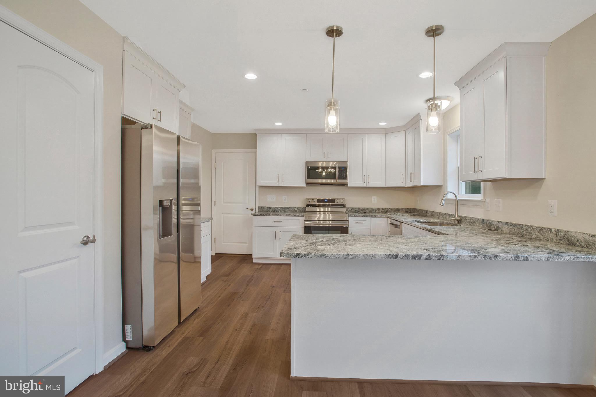 11541 Bootstrap Trail Lusby, MD 20657 - Photo 10 of 24 a kitchen with stainless steel appliances granite countertop a refrigerator a sink dishwasher a stove and white cabinets with wooden floor