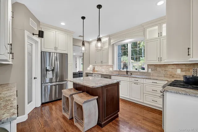 a kitchen with stainless steel appliances granite countertop a refrigerator a sink dishwasher a stove and white countertops with wooden floor