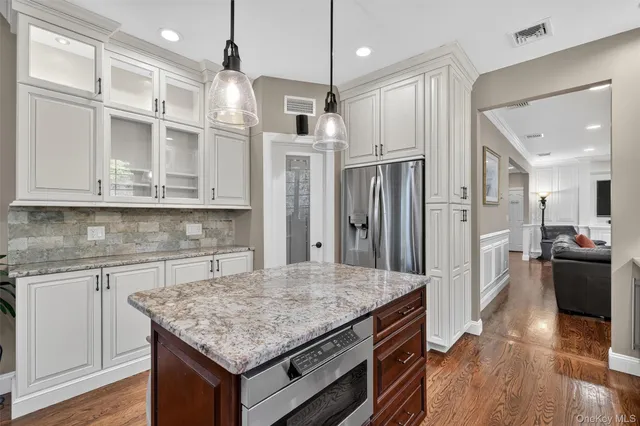 a kitchen with stainless steel appliances granite countertop a refrigerator a stove and a wooden floors