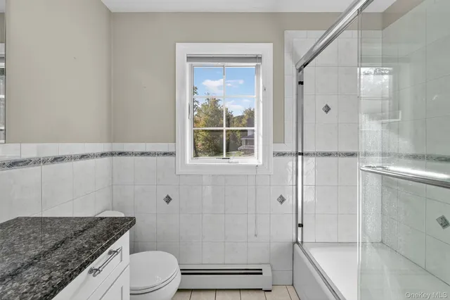 a bathroom with a granite countertop bathtub shower sink vanity and toilet