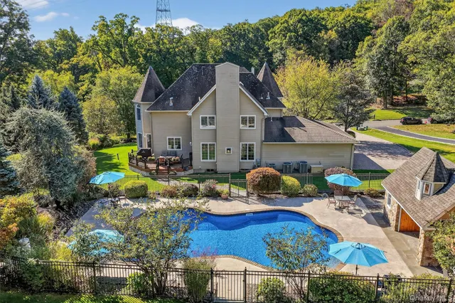 an aerial view of a house with swimming pool and large trees
