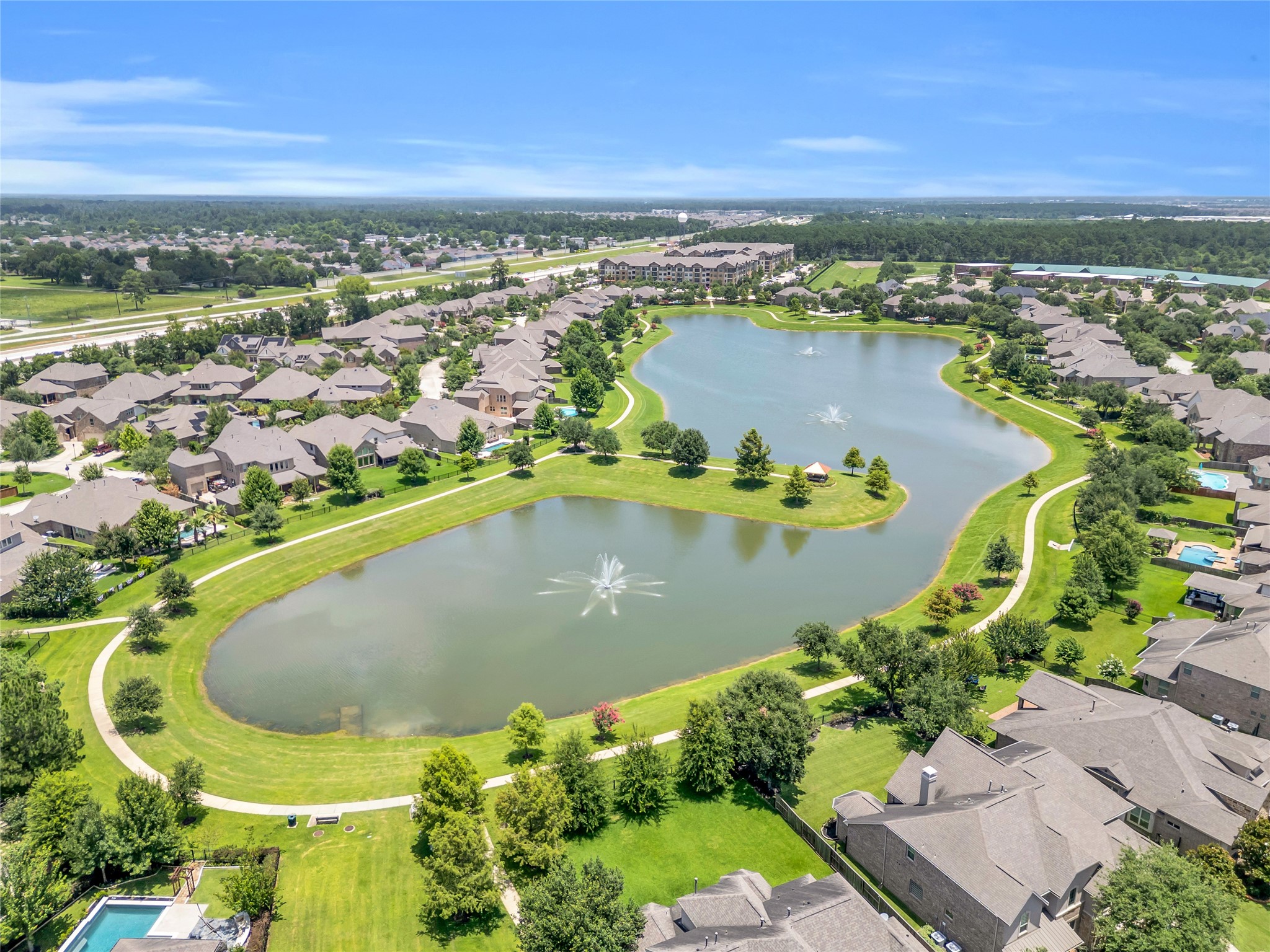9842 Kirkstone Terrace Drive Spring, TX 77379 - Photo 28 of 34 serene residential neighborhood with a large, central lake featuring fountains. The area is surrounded by well-maintained homes, lush greenery, and walking paths, Club house, pool, fitness center and more! offering a picturesque living environment. Great walking trails.