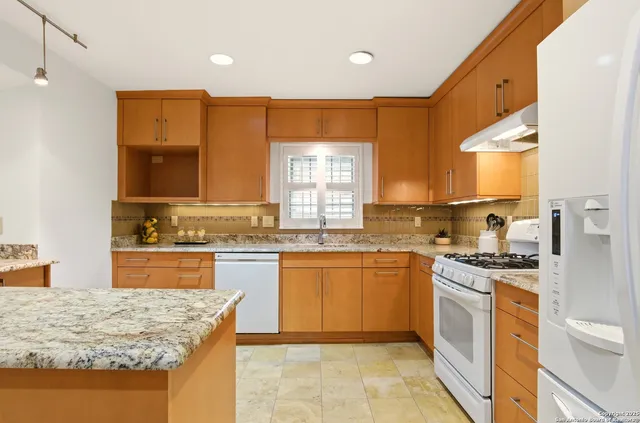 a kitchen with stainless steel appliances granite countertop wooden cabinets and a granite counter tops with a large window