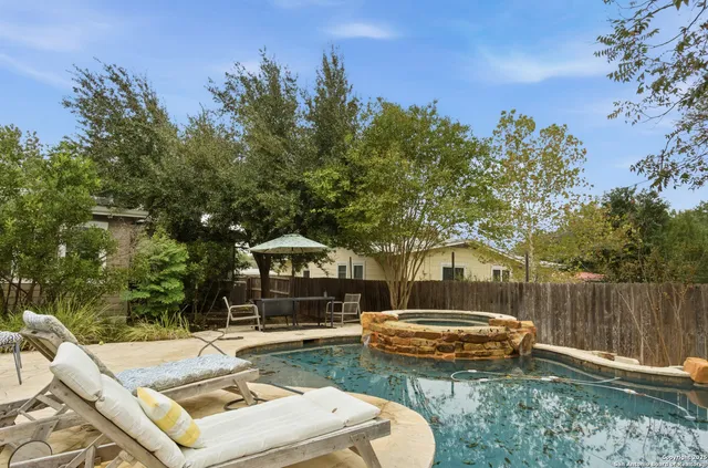 a view of a backyard with couches plants and large trees
