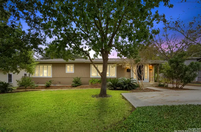 a front view of a house with a yard and trees