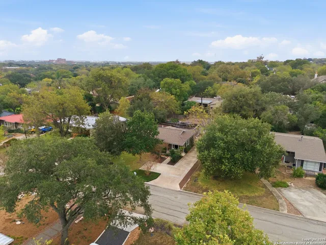 an aerial view of residential houses with outdoor space and trees