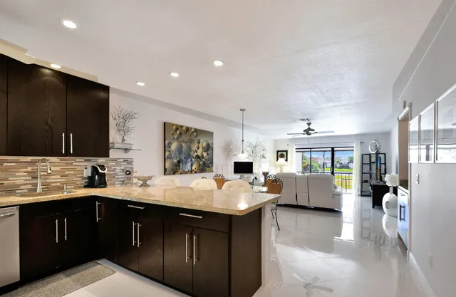 a large white kitchen with a large window and stainless steel appliances