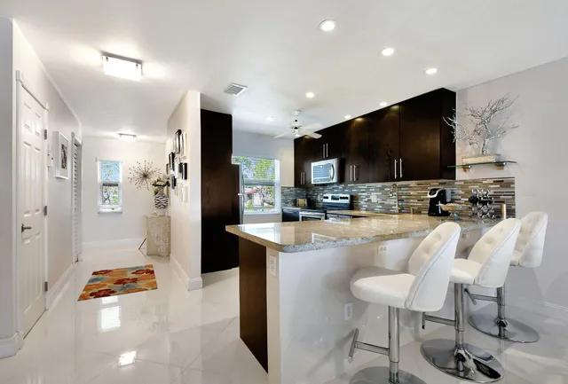 a kitchen with stainless steel appliances kitchen island granite countertop a refrigerator and a stove top oven