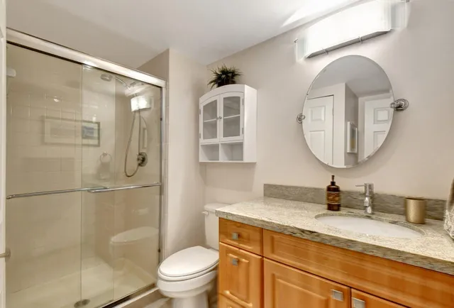 a bathroom with a granite countertop sink mirror toilet and shower