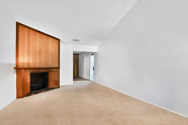 a view of an empty room with a fireplace and a window