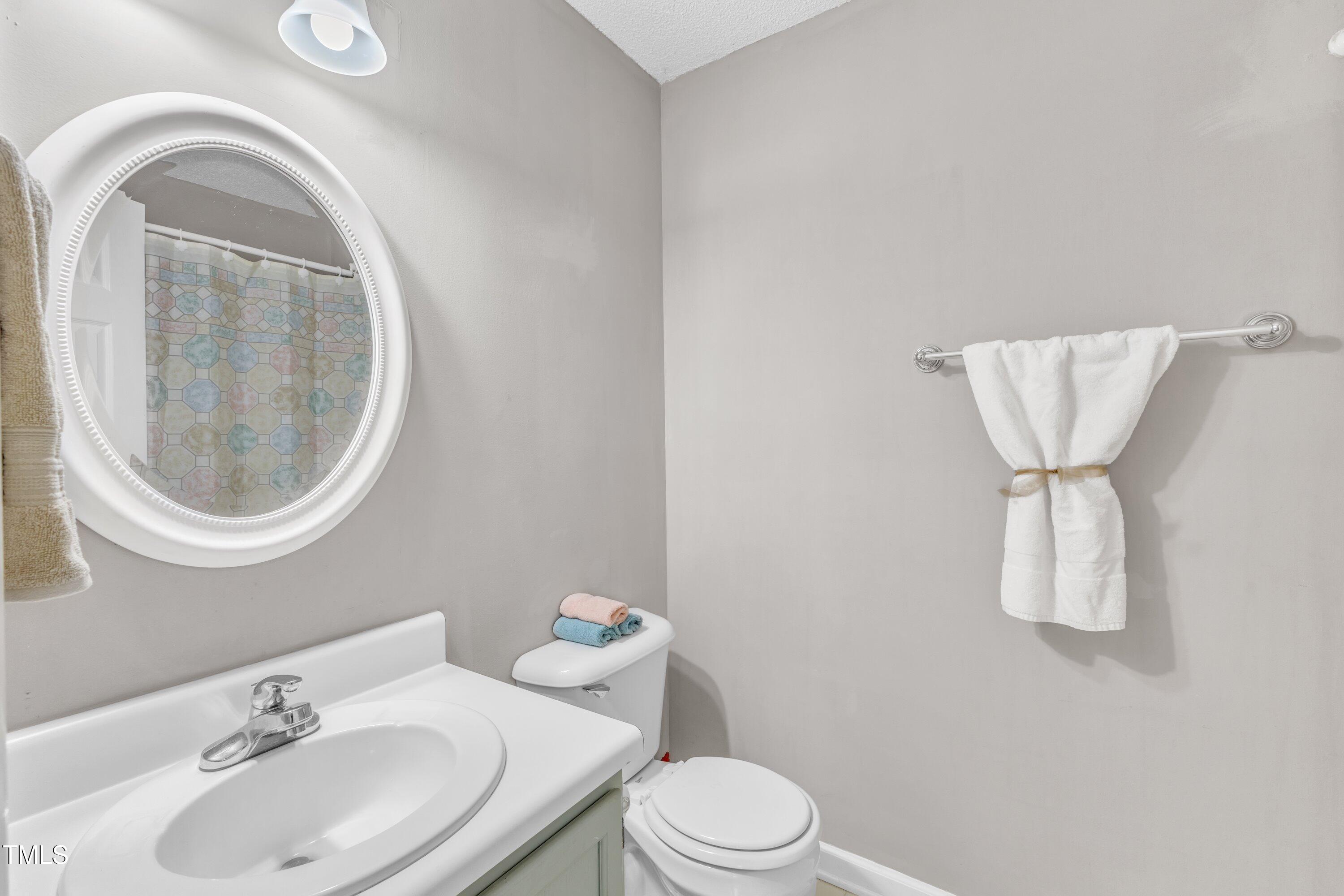4533 Whistling Way Raleigh, NC 27616 - Photo 12 of 25 a bathroom with a toilet sink a mirror and vanity