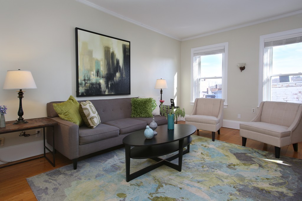a living room with furniture a lamp paintings and a window