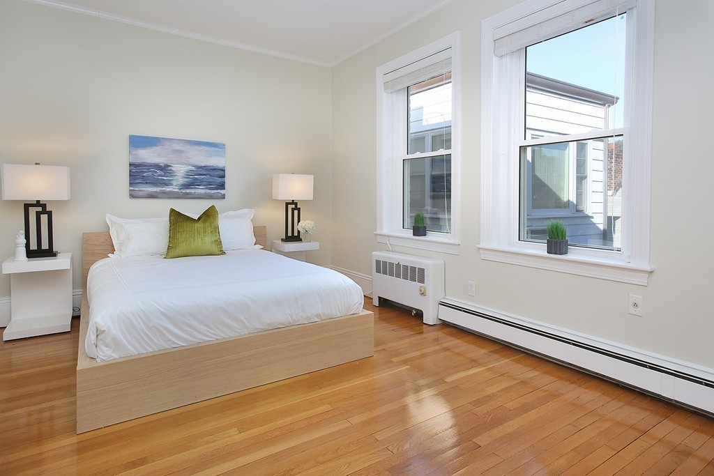 21 Warwick Road, Unit 6 Brookline, MA 02445 - Photo 4 of 10 a bedroom with a bed wooden floor and window