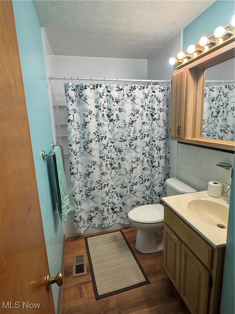 8810 Auburn Road Chardon, OH 44024 - Photo 16 of 22 Full bath with vanity, a textured ceiling, dark wood-style floors, a shower with curtain, and tile walls