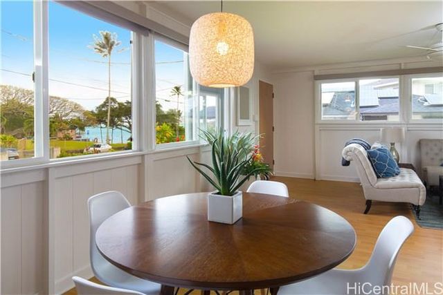 a view of a dining room with furniture a potted plant and a large window
