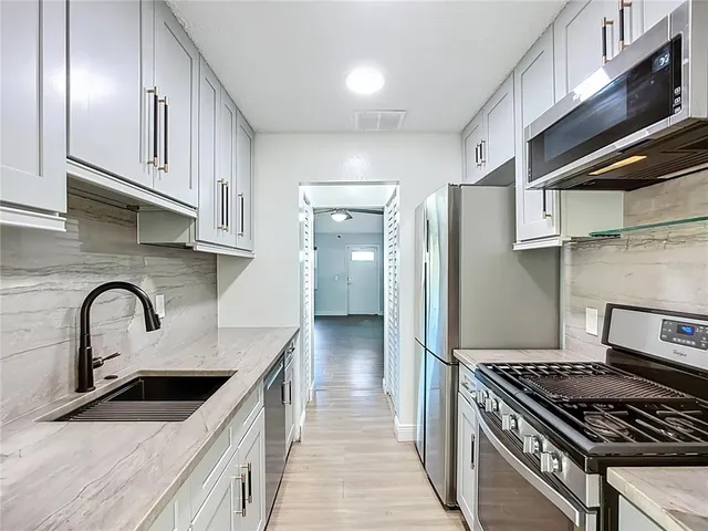 a kitchen with stainless steel appliances granite countertop a refrigerator and a stove top oven