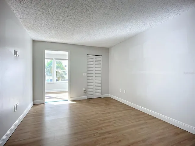 a view of an empty room with wooden floor and closet