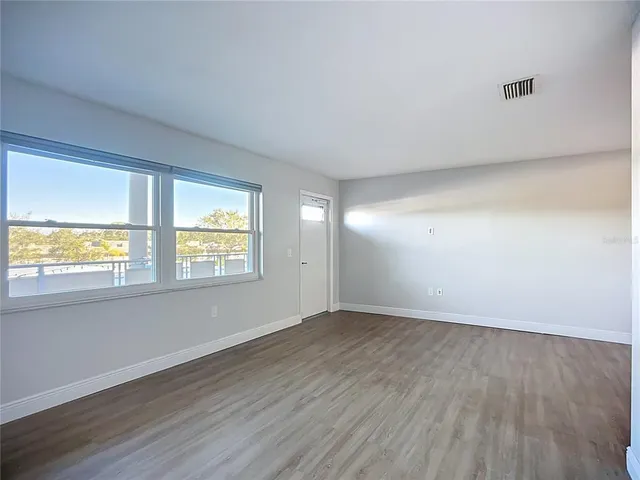 an empty room with wooden floor cabinet and windows