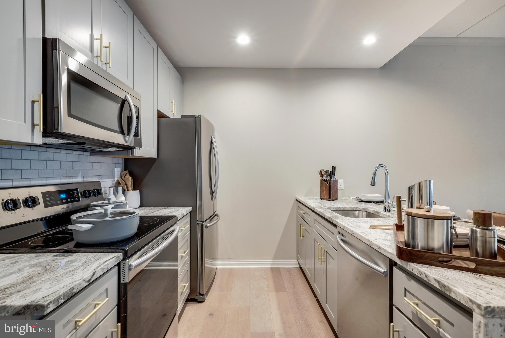 30 North 23rd Street, Unit 2207 Philadelphia, PA 19103 - Photo 3 of 42 a kitchen with stainless steel appliances granite countertop a sink stove microwave and refrigerator