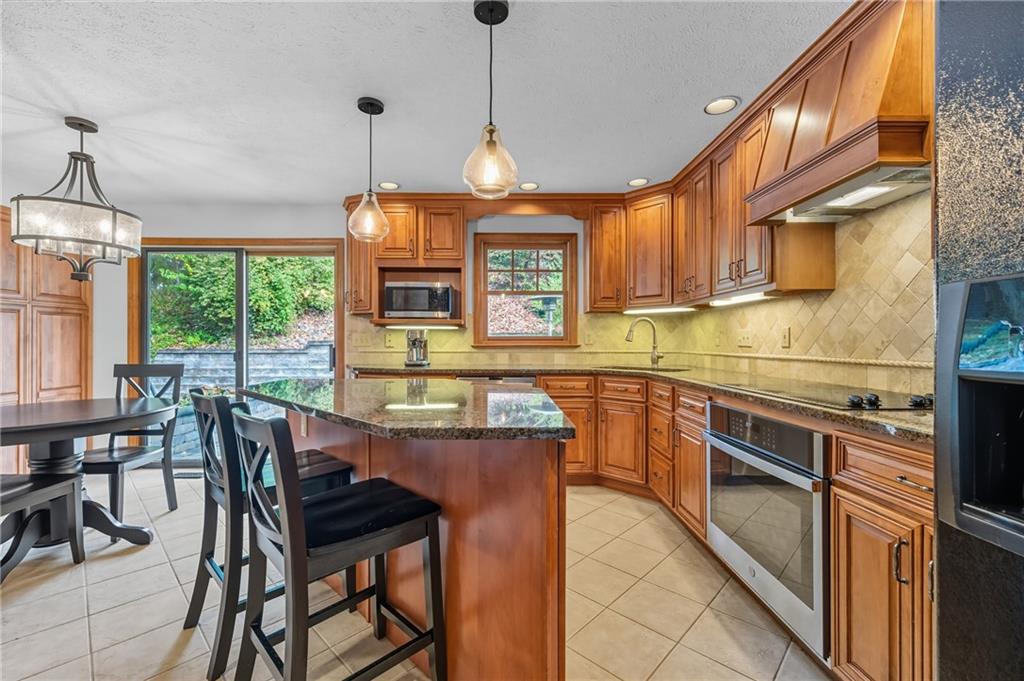 122 Rippling Brook Drive Sewickley, PA 15143 - Photo 6 of 31 a kitchen with stainless steel appliances granite countertop wooden cabinets a dining table and chairs