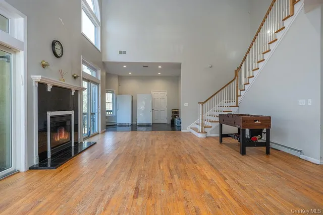 a big room with wooden floor fireplace and windows