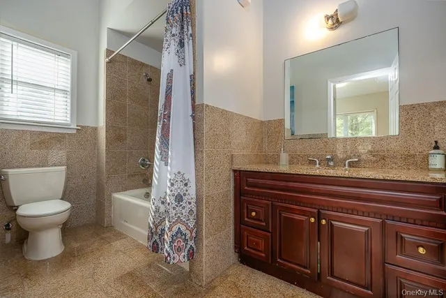 a bathroom with a granite countertop toilet sink and a window