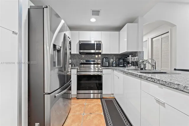 a kitchen with stainless steel appliances granite countertop a refrigerator stove and sink