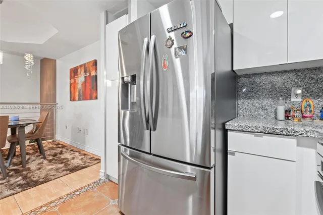 a metallic refrigerator freezer sitting inside of a kitchen