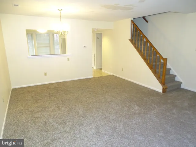 a view of an empty room with wooden floor and stairs