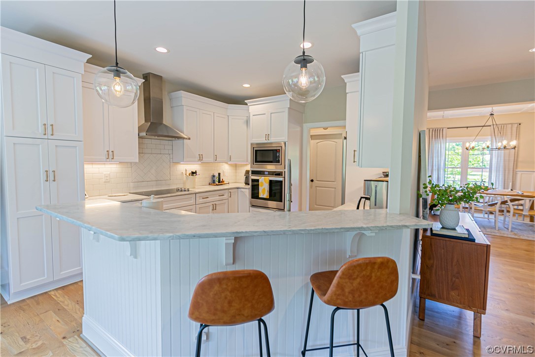 10337 Georgetown Road Mechanicsville, VA 23116 - Photo 21 of 50 Gourmet Kitchen with a kitchen breakfast bar, ventilation hood, electric stovetop, microwave, oven, pendant lighting,Marble countertops, white cabinetry, and light hardwood floors!