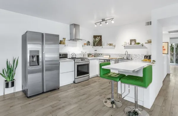a kitchen with stainless steel appliances a sink a stove a refrigerator cabinets and wooden floor