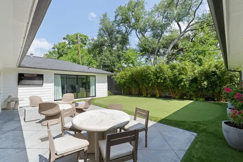 a view of a patio with table and chairs potted plants and floor to ceiling window