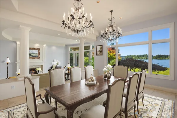 a view of a dining room with furniture a chandelier and large windows