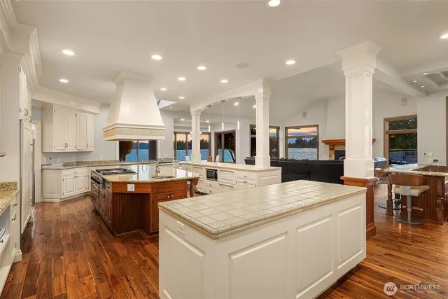 a large kitchen with kitchen island a stove a sink a refrigerator and a dining table with wooden floor