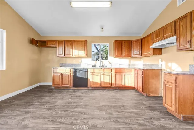 a large kitchen with granite countertop a sink window and cabinets