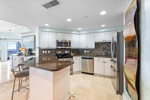 a kitchen with stainless steel appliances a stove top oven a sink a dining table and chairs