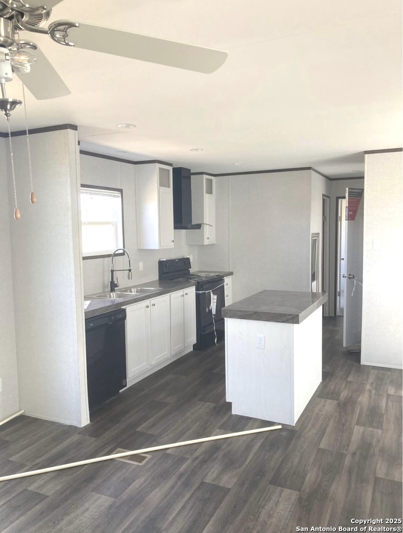 a large white kitchen with a sink dishwasher a refrigerator and white cabinets with wooden floor