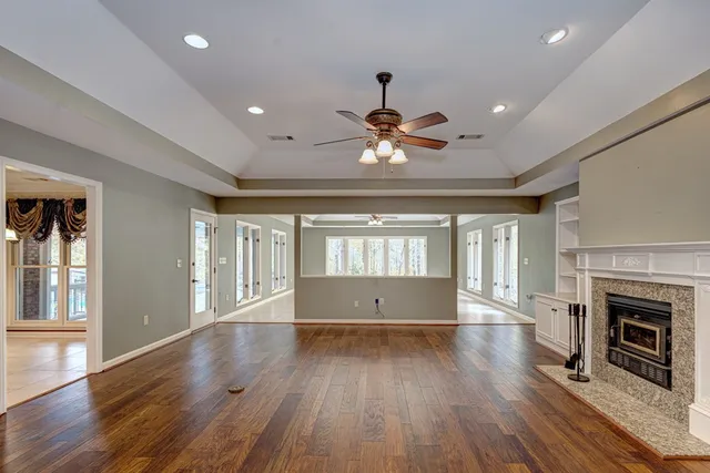an empty room with wooden floor fireplace and windows