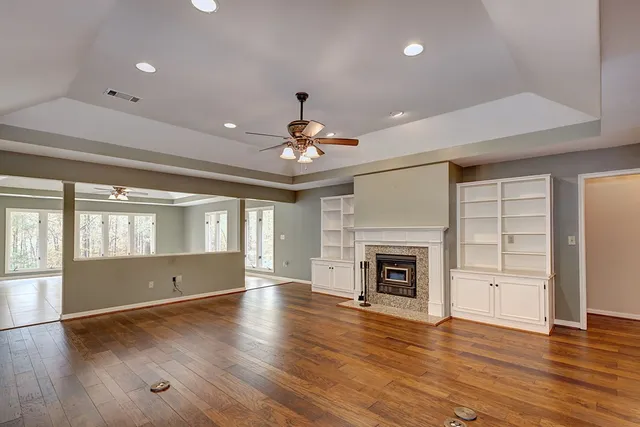 an empty room with wooden floor fireplace and windows