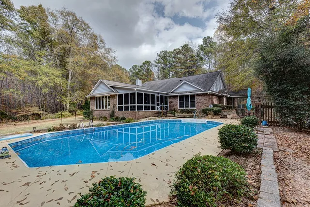 a view of a house with pool and trees in the background