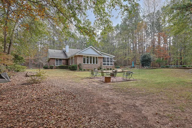 an aerial view of a house with a yard and trees all around