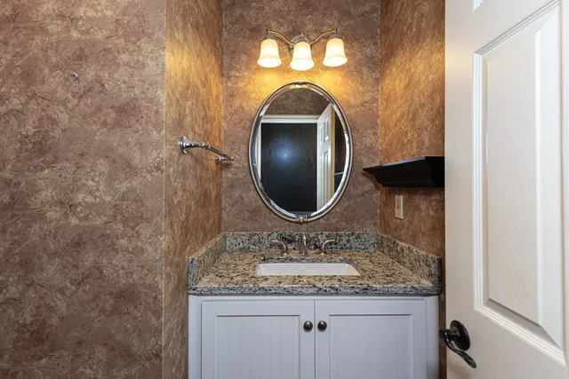 a bathroom with a granite countertop sink a mirror and vanity