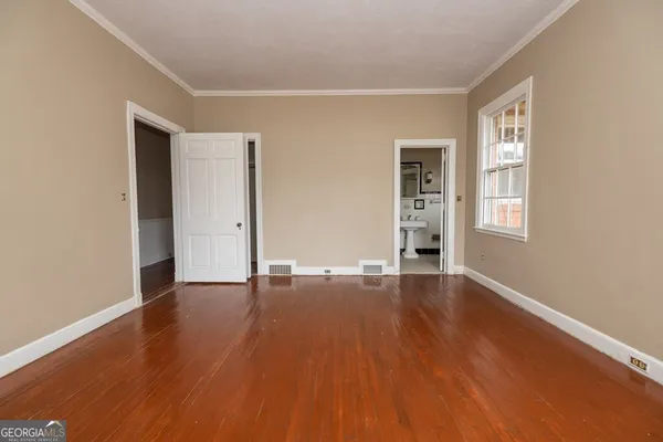 an empty room with wooden floor and windows