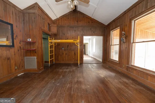 a view of empty room with wooden floor and fan