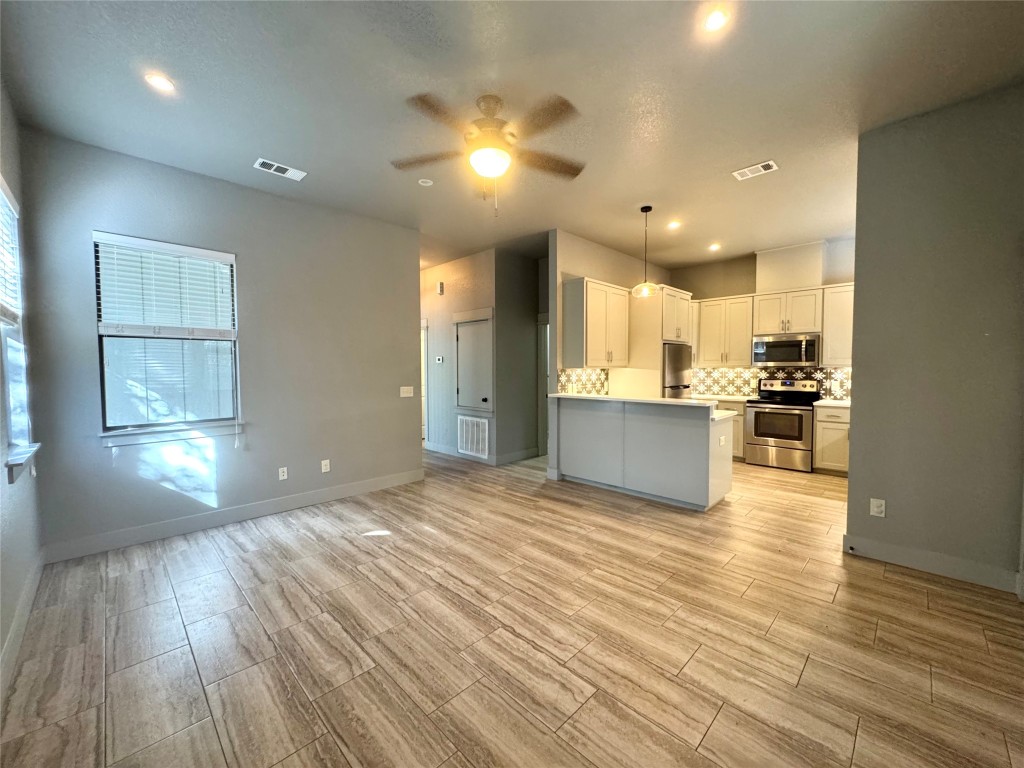 290 Hugo Road, Unit A San Marcos, TX 78666 - Photo 6 of 25 a view of an empty room and kitchen with wooden floor